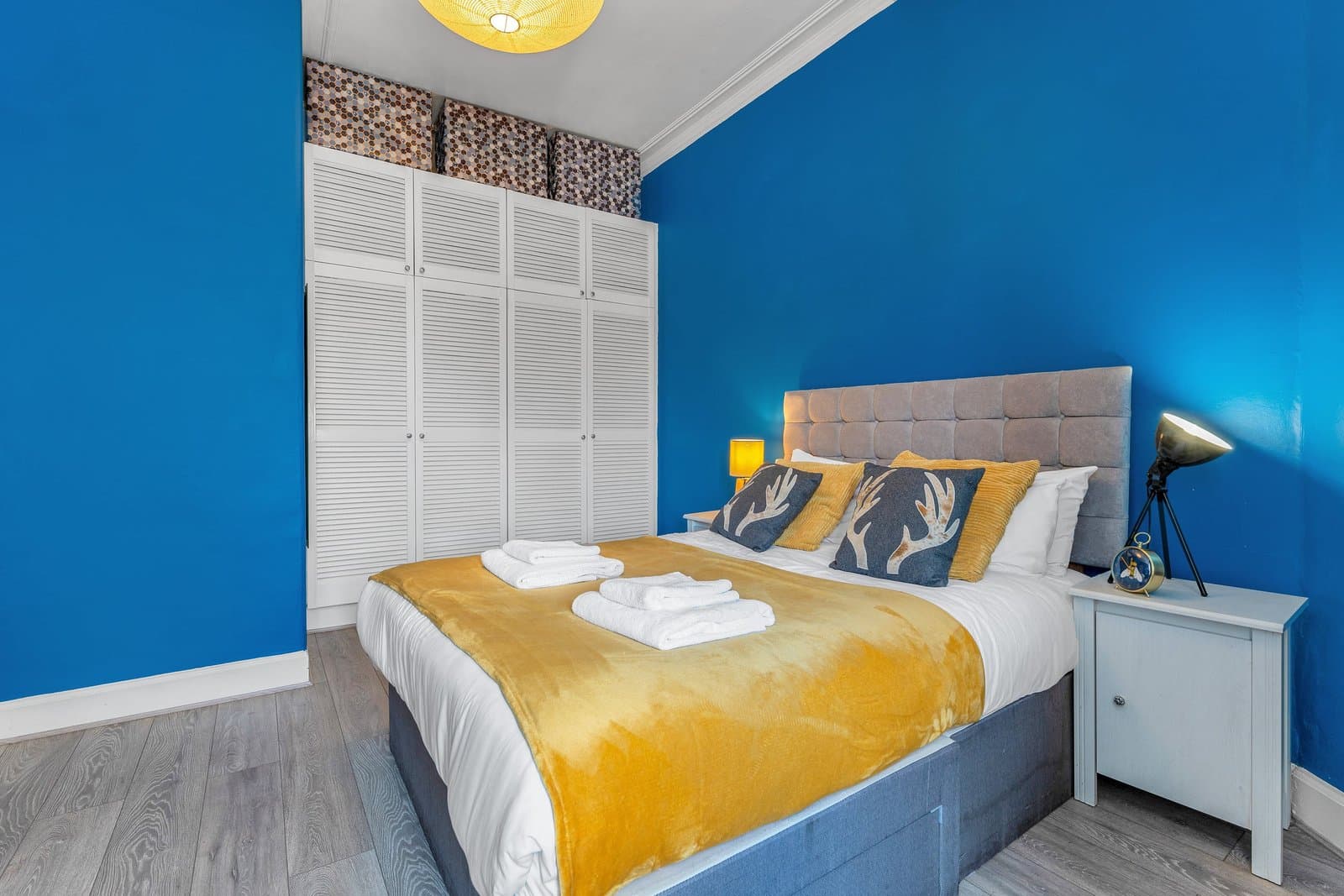 The king-size bed with antler cushions, bedside lamps and built-in wardrobes behind