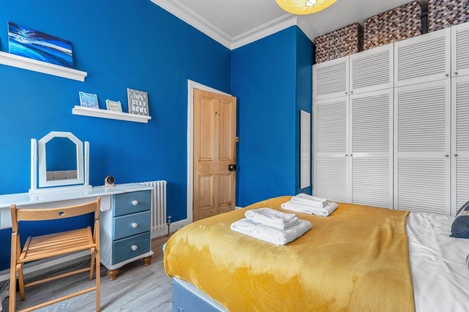 A dressing table and chair in the bedroom, beside louvred built-in wardrobes