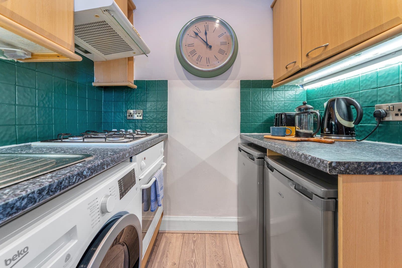 The kitchen, with green tiles, a gas hob, oven and washing machine