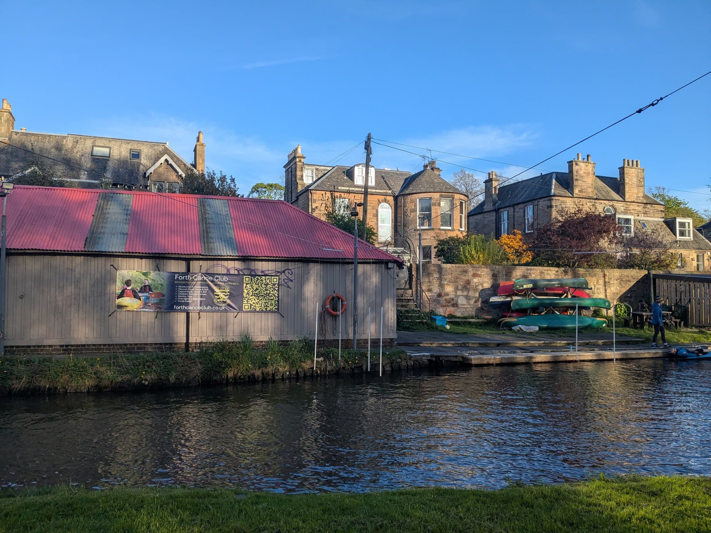 The Union Canal a few minutes from the flat, with a red-roofed boathouse, canoes and sandstone villas on the far bank